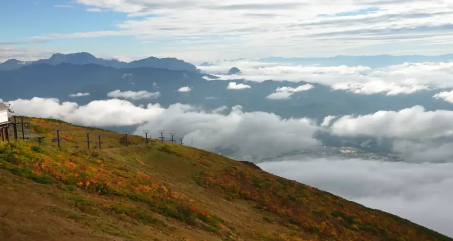 Autumn colours on the Happo-ike trail with ski lifts and clouds below